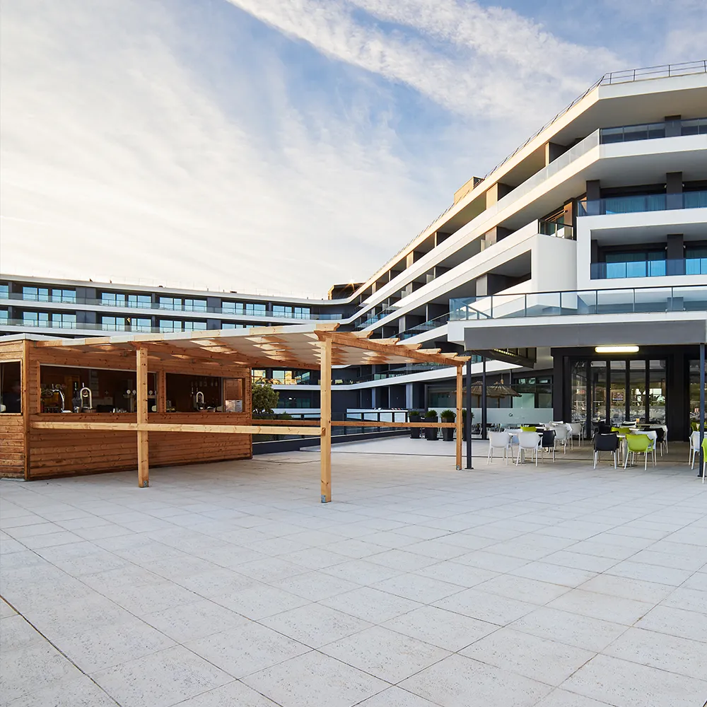 Pool bar at Alvor Baía Resort Hotel, with an outdoor terrace, tables and chairs next to the pool area.