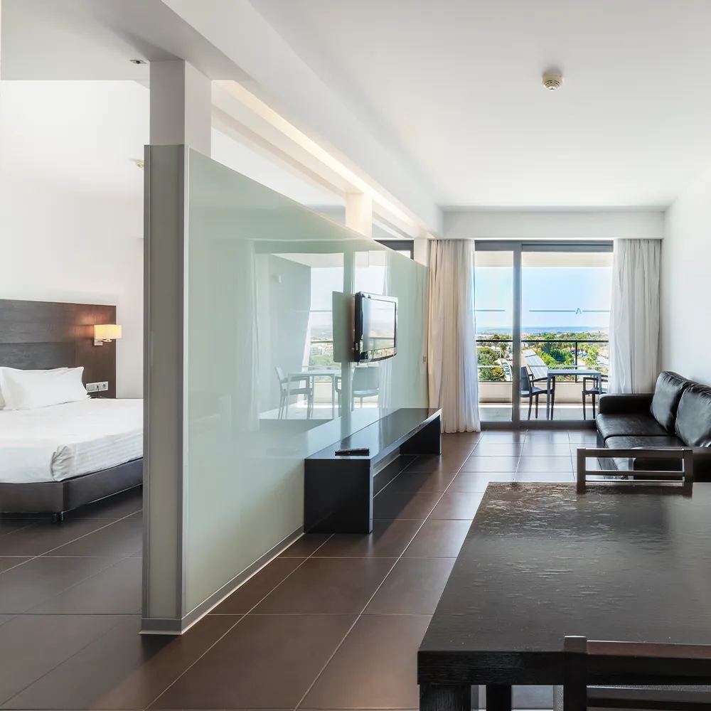 Zona de estar de la Suite Classic del Alvor Baía con sofá, televisión y zona de comedor.