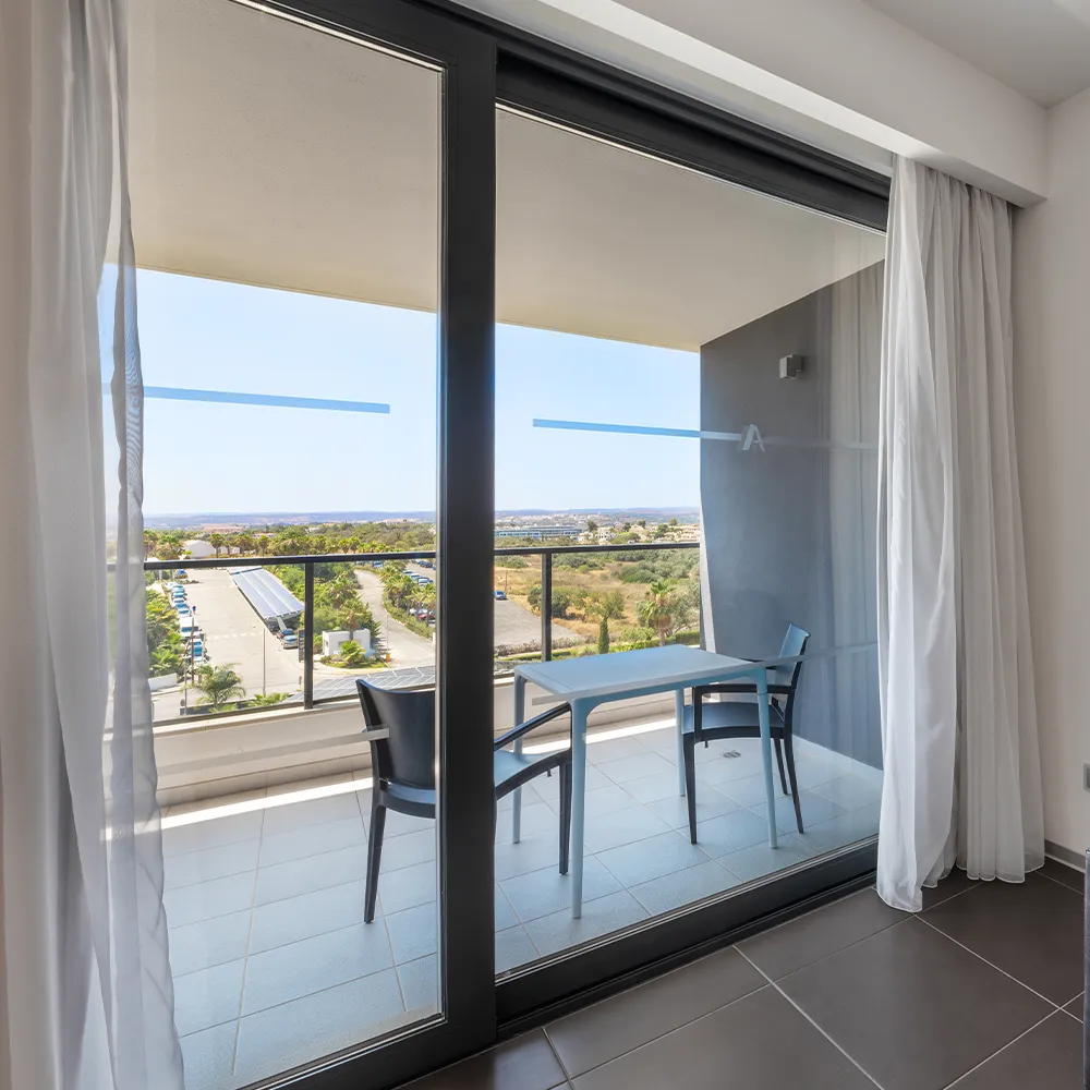 Zona de estar de la Suite Classic del Alvor Baía con sofá y balcón con vistas al interior.