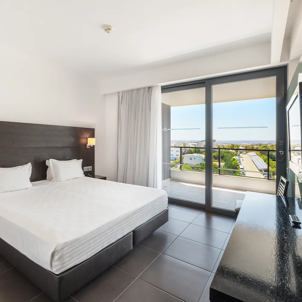 Dormitorio de la Suite Classic del Alvor Baía con cama de matrimonio y balcón con vistas al interior.