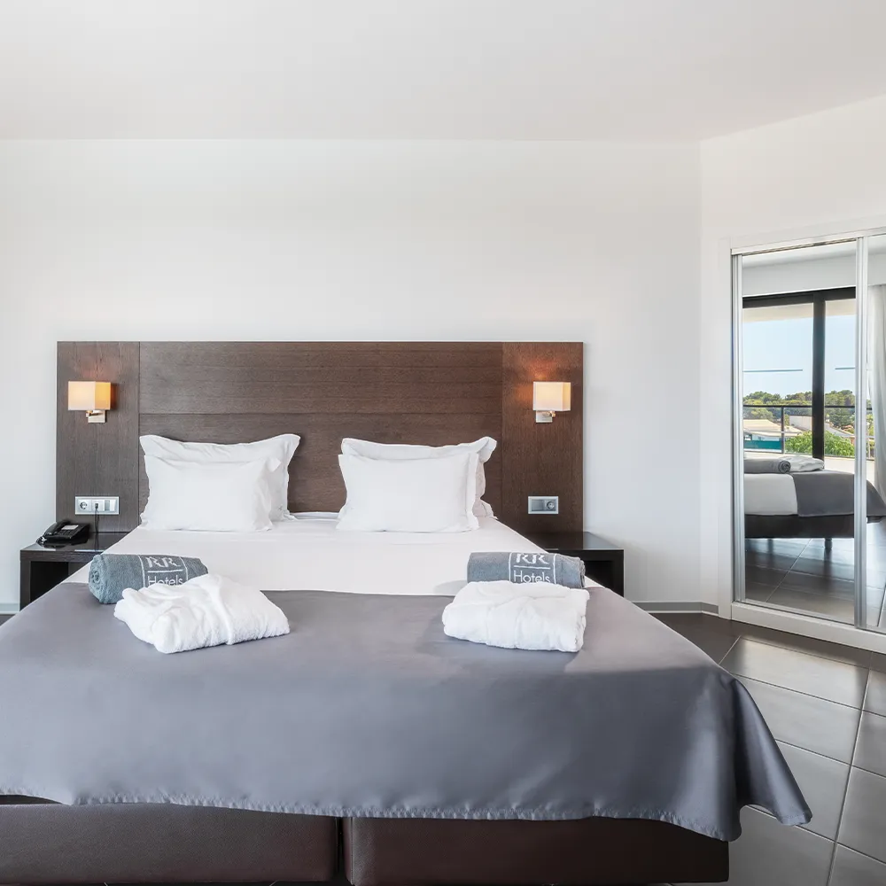 Cama de casal da Suite Club do Alvor Baía com roupões e toalhas de piscina de cortesia.