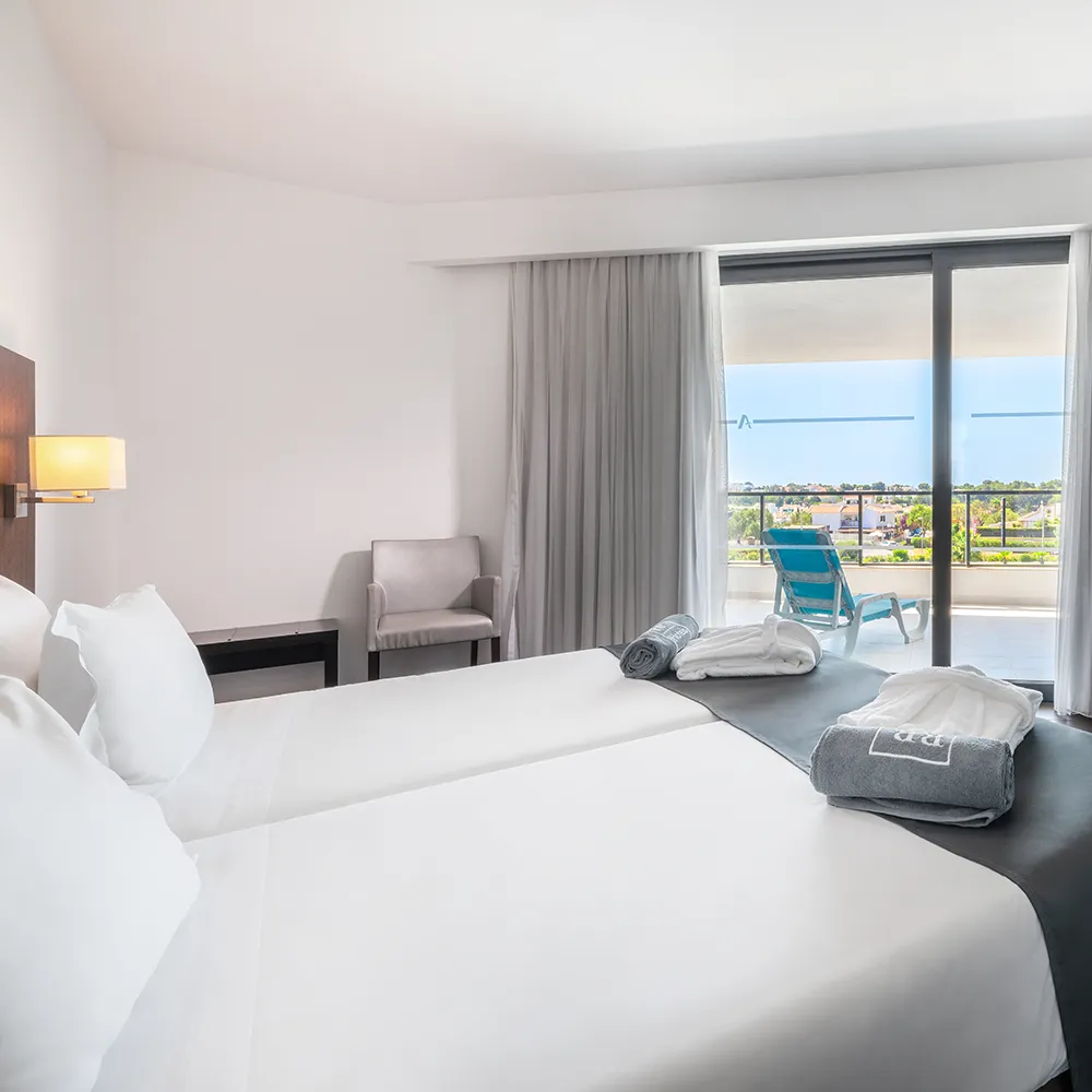 Segundo quarto da Suite Club do Alvor Baía com camas twin e acesso à varanda.