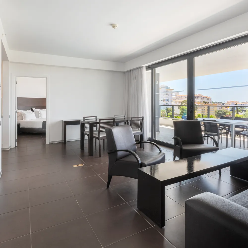 Vista geral da Suite Club do Alvor Baía com sala de estar espaçosa e acesso à varanda.