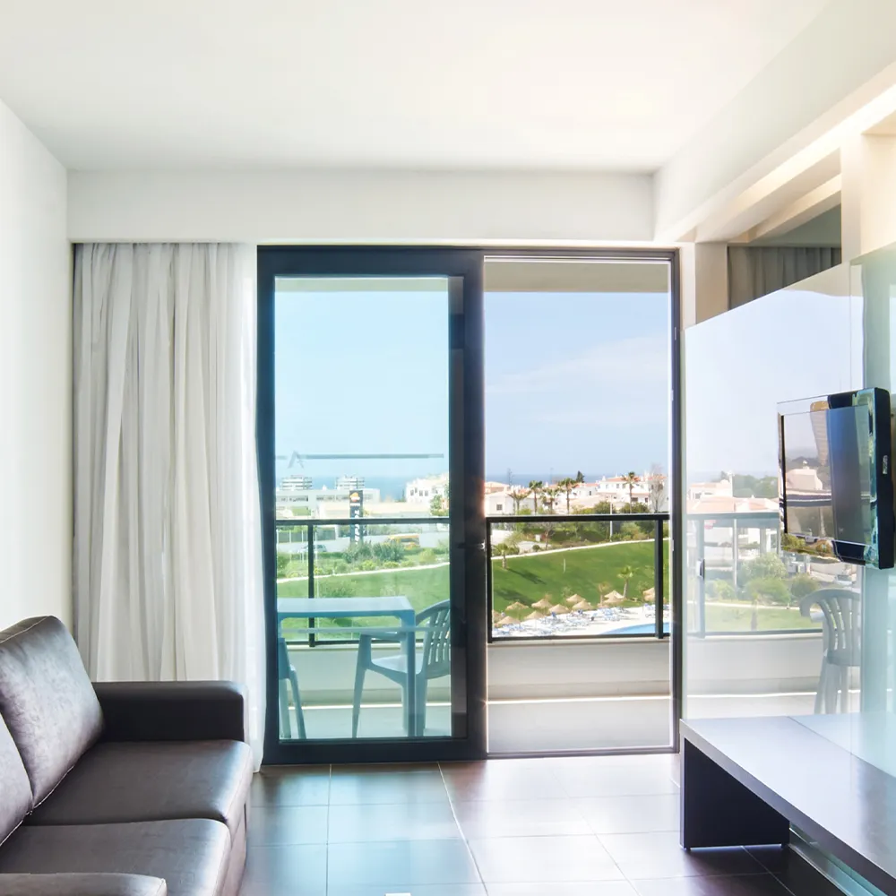 Vista da sala de estar da Suite Prestige do Alvor Baía com sofá e TV.