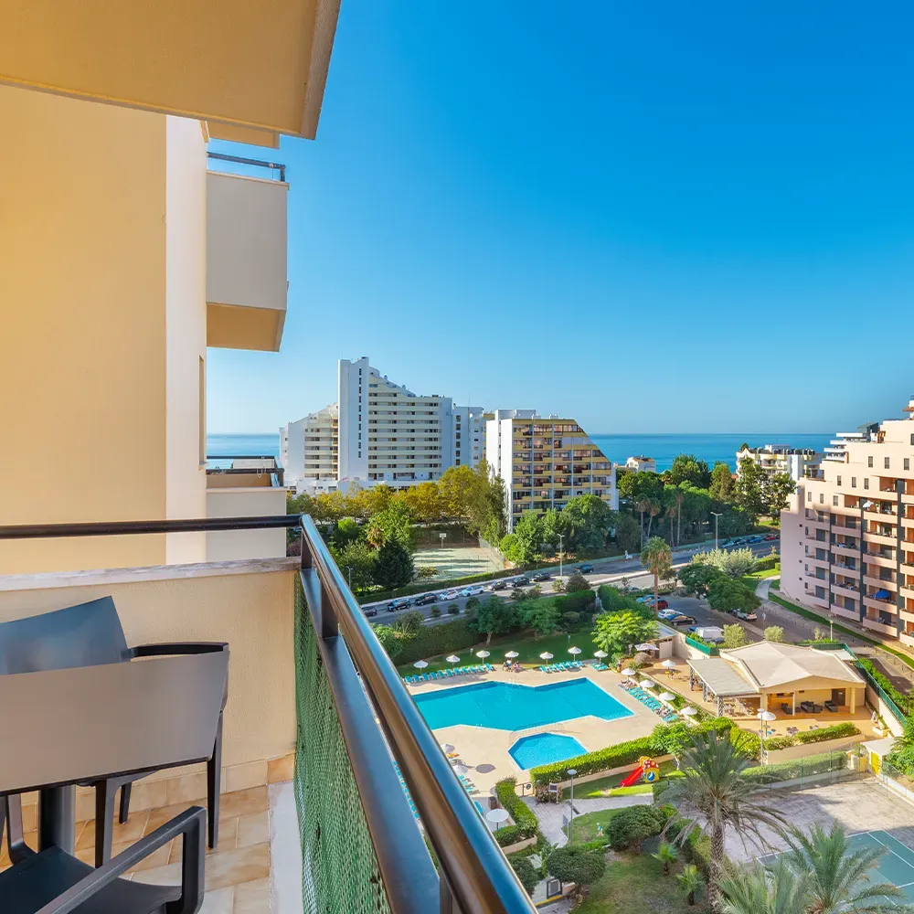 Balcon privé avec table, chaises et vue sur la piscine.