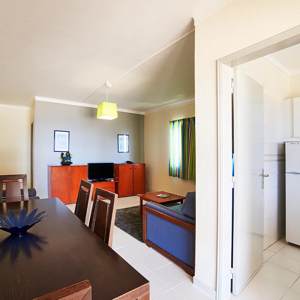 Sala de estar e zona de refeições de apartamento com acesso à cozinha.