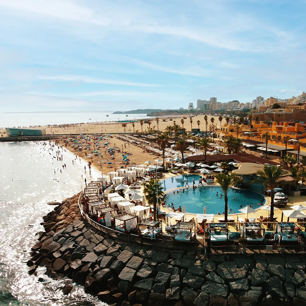 Aerial view of NoSoloÁgua Beach Club with the swimming pool, beach and Portimão marina.