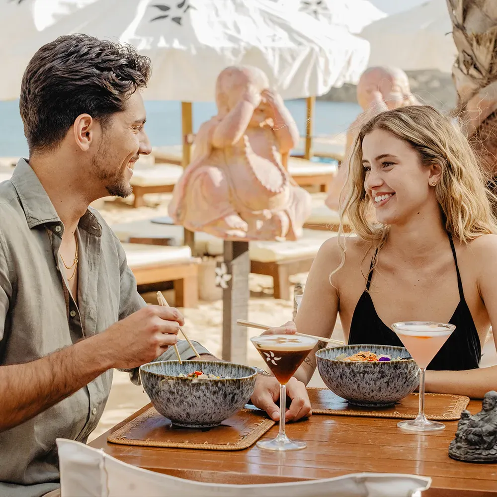 Couple toasting with cocktails on the terrace of NoSoloÁgua Beach Club restaurant in Portimão.