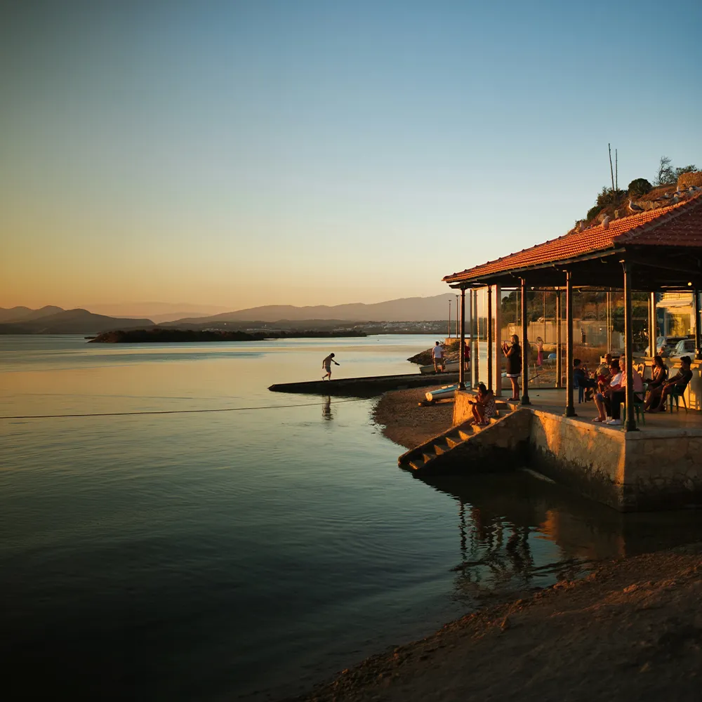 Alvor Fish Market at sunset, by the water, with boats and outdoor seating.