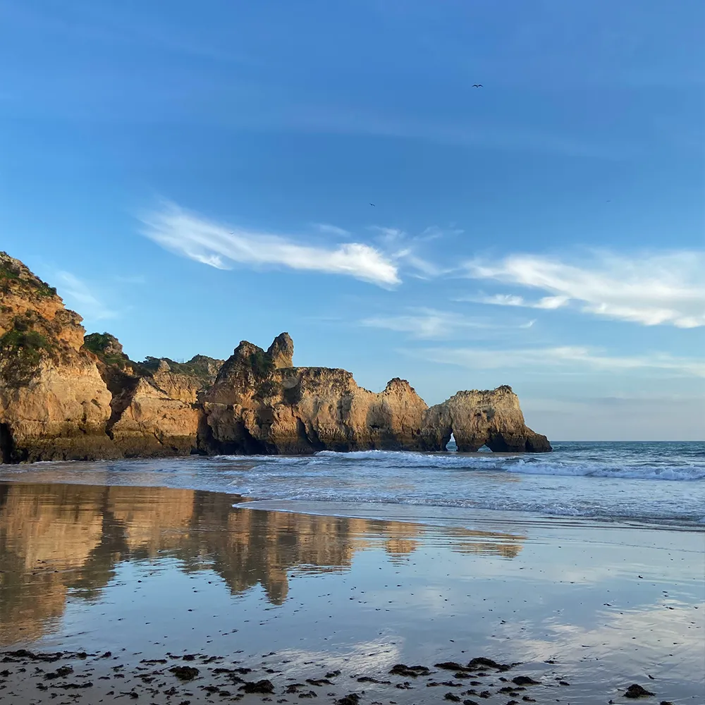Alvor Beach with cliffs and rock formations by the sea.
