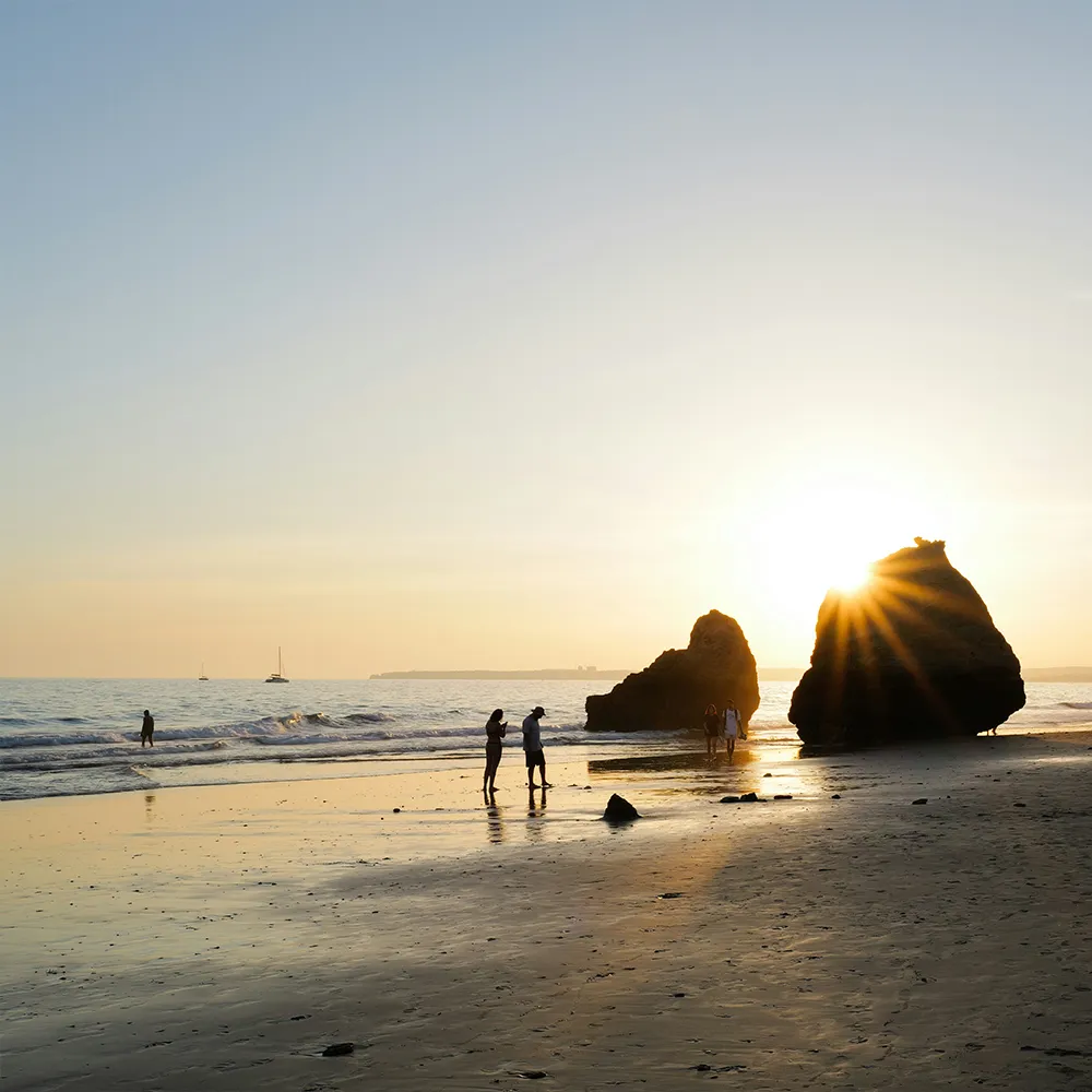 Alvor Beach at sunset, with rock formations by the sea.
