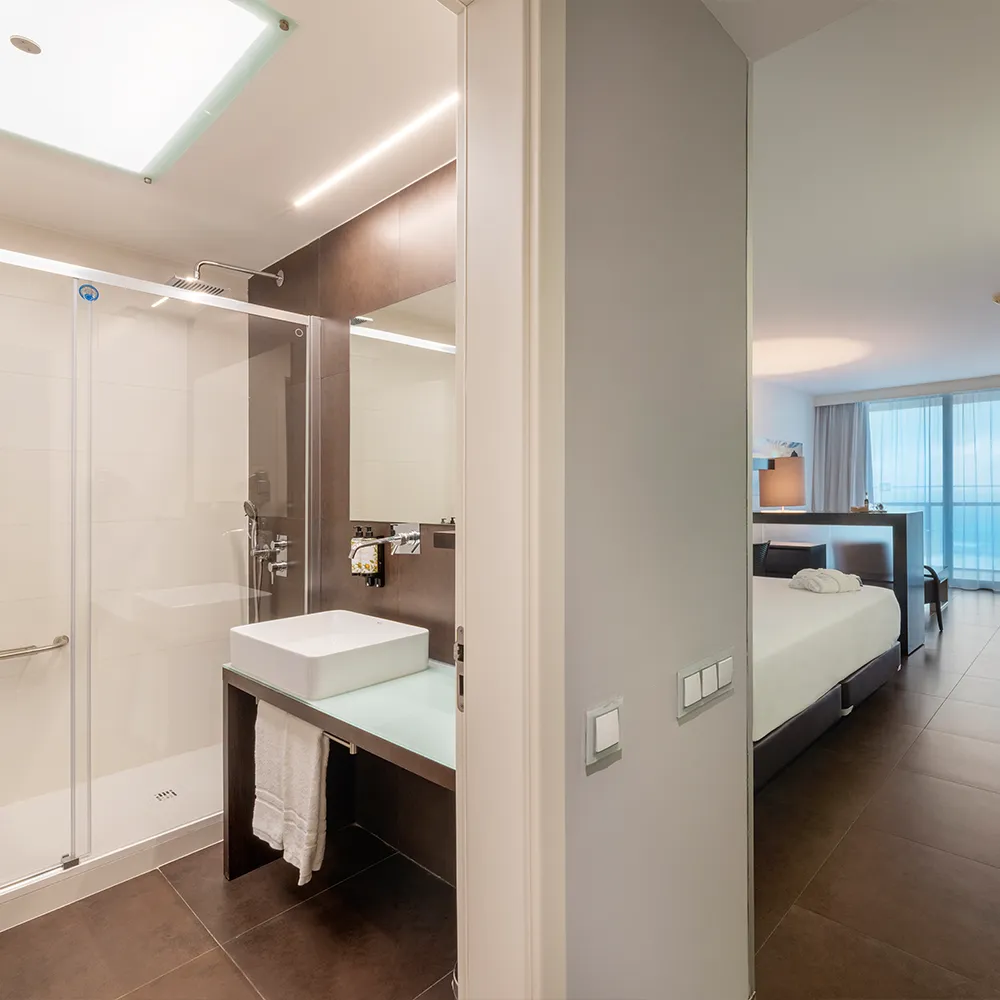 Entrada de uma suite com vista mar no RR Hotel da Rocha, com casa de banho com poliban em primeiro plano.